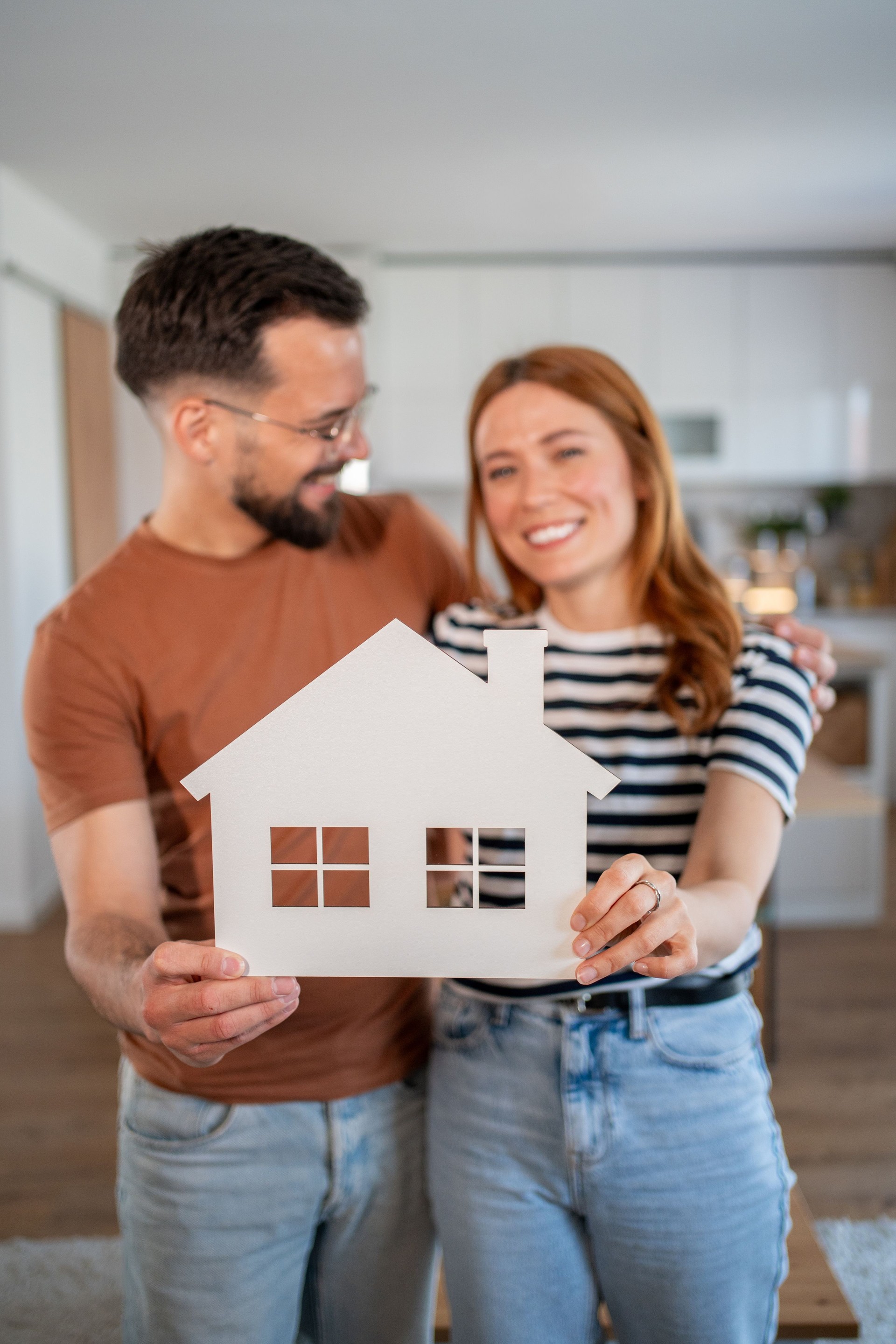 Happy couple holding a paper house: embracing the dream of homeownership